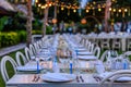 Set table for a white and blue beach wedding dinner decorated with shells, evening lights. Royalty Free Stock Photo