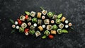 Set of tasty sushi and maki rolls on black stone background. Japanese food. Top view.