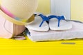 A set of things for travel and recreation,flip-flops, a towel, a hat, on a yellow suitcase, on a wooden background