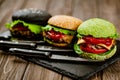 Set of three color homemade burgers with marble beef with knifes on wooden table. Selective focus Royalty Free Stock Photo