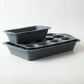 A set of three dark gray baking tins stacked together. The top tin is a rectangular loaf Royalty Free Stock Photo