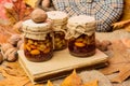 Set three honey natural sweets in jars red background covered fallen leaves. Jars walnuts and fallen leaves. Storehouse