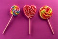 Set of three lollipops with rainbow colour and fruit flawor with purple background