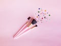 Set of three makeup brushes on a pink background, top view with copy space. Cosmetic products.