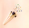 Set of three makeup brushes on a pink background, top view with copy space. Cosmetic products.