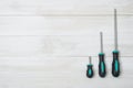 Set of three screwdrivers lying on a white wooden surface Royalty Free Stock Photo