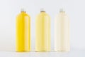 Set of three transparent plastic tall bottles with different yellow color drink and silver cap mockup on white background. Royalty Free Stock Photo