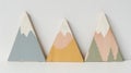 A set of three wooden wall hangings in the shape of mountain peaks each painted in muted pastel colors. .