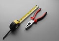 A set of tools on a gray surface includes a metal tape measure with a yellow and black plastic Royalty Free Stock Photo