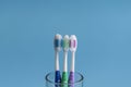 Set of toothbrushes in glass on blue background. Cup with toothbrushes against color background. Dental care Royalty Free Stock Photo