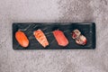 Set of traditional japanese nigiri sushi on the black plate on gray concrete background - with raw tuna, salmon fish Royalty Free Stock Photo