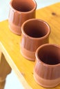 Set of traditional spanish red clay glazed earthenware cups on wooden table. Mediterranean kitchen interior decoration style