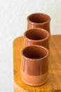 Set of traditional spanish red clay glazed earthenware cups on wooden table. Mediterranean kitchen interior. Local artisanal craft