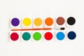 Set of twelve colorful watercolors with brush on a white surface