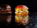 Set of two delicious burgers isolated on a dark background. The concept of fast food, delicious but unwholesome food.