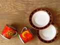 A set of two fine porcelain ware tea coffee cups in red, black and yellow and two saucers on oak wood rustic background. Royalty Free Stock Photo