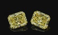 Set of two luxury yellow transparent sparkling gemstones emerald cut shape diamonds isolated on black background