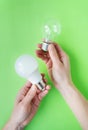 A set of two types of lamps, LED and incandescent, in the hands of a girl isolated on a green background. Energy-saving lamps Royalty Free Stock Photo