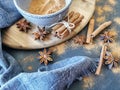 Set up view on table, decorated with dried cinnamon rolls and cinnamon powder inside a bowl, several dried aniseed flowers, rustic