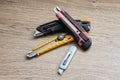 Set of utility knives and box cutters of different colors lying on a wooden surface. Concept of construction tools, office Royalty Free Stock Photo
