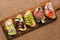 Set of a variety of sandwiches with salmon, sausage, avocado, beet, feta cheese, cucumber and radish on a cutting board. Top view