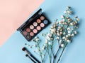 Set of various color eyeshadows for makeup with makeup brush and small white flowers. blue background Royalty Free Stock Photo