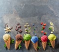 Set of various colorful ice creams in waffle cones with fruits slices on the grey background