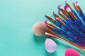Set of various professional trendy fashion violet purple metallic makeup brushes, beauty blenders on pastel green background. Royalty Free Stock Photo