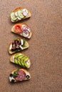 A set of various sandwiches with salmon, smoked sausage, vegetables and feta cheese on a brown stone background. Top view Royalty Free Stock Photo