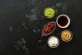 Set of various sauces in bowls on a black stone background. Mustard sauce, tomato, wasabi, mayonnaise, soy. Top view, copy space Royalty Free Stock Photo