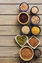 A set of various superfoods , whole grains,beans, seeds, legumes in bowls on a wooden plank table. Top view, copy space