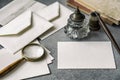 Set of vintage writing stationery items, wooden pen, inkwell, magnifier and envelopes, letters closeup. Royalty Free Stock Photo