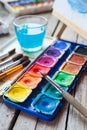 Set of watercolor paints, art brushes, glass of water and easel Royalty Free Stock Photo