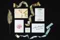 Set of wedding decorations: calligraphy, invitation cards, envelope, lace and ribbons on black background. Flat lay, close up. Rus Royalty Free Stock Photo