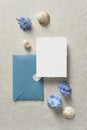 Set of wedding invitation card and blue envelope with seashells on beige table. Save the date sea style design. Nautical wedding