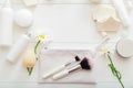 Set white cosmetic products on wooden table with flowers as frame. Beauty makeup brushes skincare hair treatment cosmetic