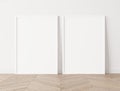 Set of 2 white frames a3, a4, frame mock up on white wall standing on wooden floor. Royalty Free Stock Photo