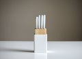 Set of white kitchen knives in a wooden knife block on table , isolated on a gray Royalty Free Stock Photo