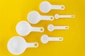 Set of white measuring cups, measuring spoons use in cooking lay on wooden yellow background