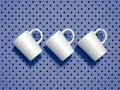 Set of white mugs hanged on metal hooks. 3d rendering. Royalty Free Stock Photo