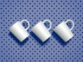 Set of white mugs hanged on metal hooks. 3d rendering.