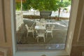 Set of white plastic furniture stands in the patio, view through large glass Windows Royalty Free Stock Photo