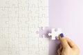 Set of white puzzle pieces and hand holding last one piece on purple background Royalty Free Stock Photo