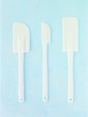 Set of white rubber spatula over blue background. Three pieces of silicone kitchen utensils