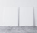 Set of 2 white vertical modern frames A3, A4, frame mock up on white wall standing on gray floor.