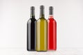 Set wine bottles different colors - red, green, black- on white wooden board, mock up. Royalty Free Stock Photo