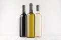 Set wine bottles different colors - transparent, green, black- on white wooden board, mock up. Royalty Free Stock Photo