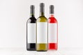 Set wine bottles - red, green, black- with blank white labels on white wooden board, mock up. Royalty Free Stock Photo