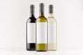 Set wine bottles - transparent, green, black- with blank white labels on white wooden board, mock up. Royalty Free Stock Photo