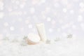 Set of winter skin care cosmetic products in snow and snowflakes on white background with bokeh lights. Face cream jar and hand